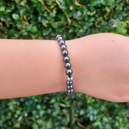 Hematite 6mm Bead Bracelet on child's hand with green hedge behind